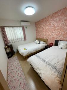 duas camas num quarto com papel de parede rosa em 新世界步行5分钟 难波电车2分钟一户建 带停车场 em Osaka