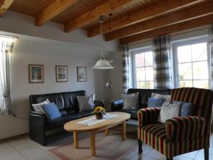 un soggiorno con divani in pelle nera e un tavolo di Ferienhaus in Nessmersiel 20-080 a Nessmersiel Altre 9 foto