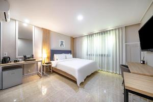 慶州市にあるBrown Dot Hotel Angangの白いベッドとテレビが備わるホテルルームです。