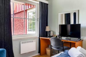 a bedroom with a desk with a computer and a window at Storebaug Hotell & Kro in Moss