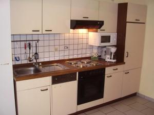 a kitchen with white cabinets and a sink and a microwave at Ferienwohnung in Dornumersiel 20-068 in Dornumersiel