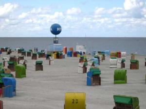 Una playa con muchas sillas de colores y una pelota azul. en Ferienwohnung in Dornumersiel 20-070, en Dornumersiel