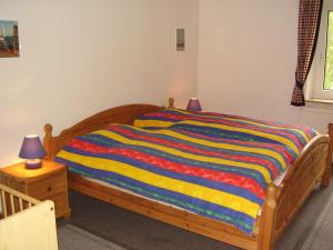 una cama de madera con una manta a rayas de colores. en Ferienwohnung in Dornumersiel 20-070, en Dornumersiel 9 fotos más