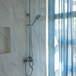 La salle de bains est pourvue d'une douche avec un pommeau de douche. dans l'établissement Silir Villa "your cozy home", à Mataram