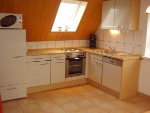 a kitchen with white cabinets and a sink and a window at Ferienwohnung in Dornumersiel 20-084 in Dornumersiel