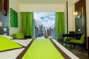 Schlafzimmer mit einem grünen Bett, einem Schreibtisch und einem Fenster in der Unterkunft Riu Plaza Panamá in Panama-Stadt