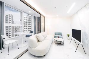 a white living room with a white couch and a tv at UH FLAT The SEOCHO in Seoul