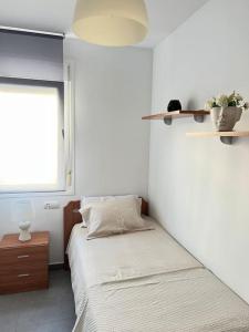 Habitación blanca con cama y ventana en Piso con terraza a 5 min del mar, en Alcanar