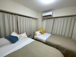 a small room with two beds and a window at サニーハイツ in Tokyo