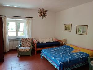 a bedroom with a bed and a chair and a window at la raganella - appartamento in Procchio