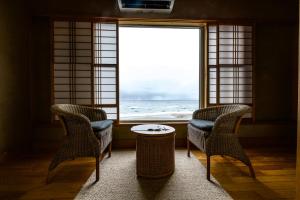 two chairs and a table in a room with a window at Wakamatsu Hot Spring Resort in Hakodate