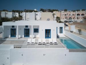 a white house with chairs and a swimming pool at Thadeos Villa with private jetted Pool in Fira