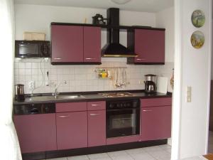 ネスマージールにあるFerienwohnung in Nessmersiel 20-041のキッチン(紫色のキャビネット、コンロ付)