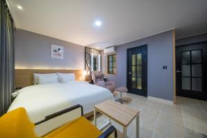 Brown Dot Hotel Angang في جيونجو: غرفة نوم بسرير ابيض كبير وكرسي اصفر