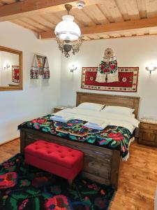 ein Schlafzimmer mit einem großen Bett mit einem roten Sitz in der Unterkunft Casuta din Cotroape in Săcel
