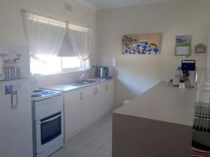 a white kitchen with a sink and a stove at Comfortable Unit Close to the Beach in Victor Harbor +5 photos
