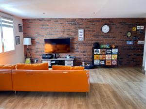 a living room with orange couches and a brick wall at Bel appartement situé près des plages. in Marseille