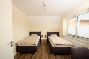duas camas num quarto com duas janelas em Ferienwohnung Schwarting em Wiefelstede