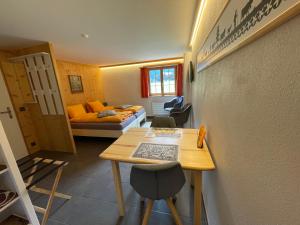 um pequeno quarto com uma mesa e um sofá em Alpenchalet Weidhaus Gstaad Ferienwohnung im Dachstock, Studio und Zimmer im EG em Gstaad