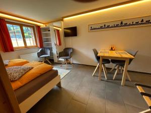 een slaapkamer met een bed en een tafel en stoelen bij Alpenchalet Weidhaus Gstaad Ferienwohnung im Dachstock, Studio und Zimmer im EG in Gstaad