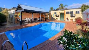 een zwembad in een tuin met een huis bij Oasis Motor Inn in Broken Hill