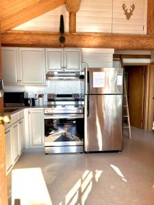 a kitchen with a stainless steel refrigerator and white cabinets at The Beach House Texada - Waterfront Cabin in Gillies Bay