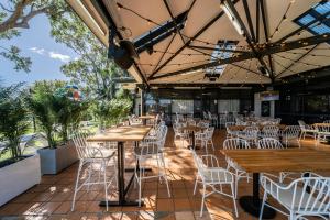 a restaurant with wooden tables and white chairs at Lakeview Hotel Motel in Shellharbour