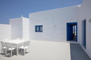 a white dining room with a white table and chairs at Thadeos Villa with private jetted Pool in Fira