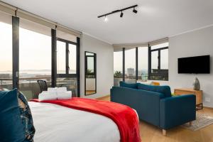 1 dormitorio con cama, sofá y ventanas en Urban Artisan Luxury Suites by Totalstay, en Ciudad del Cabo