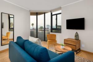 a living room with a blue couch and a tv at Urban Artisan Luxury Suites by Totalstay in Cape Town
