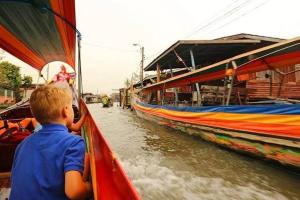 un joven mirando fuera de un barco en un río en BangkokFloatingMarket KhlongBangLuangStay en Bangkok Yai