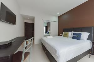 TumbangrunganにあるUrbanview Hotel Yoga Palangkaraya by RedDoorzのベッドルーム(白い大型ベッド1台、デスク付)
