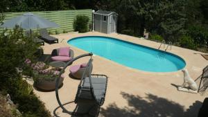 a swimming pool with chairs and an umbrella at La Bergerie in Lorgues