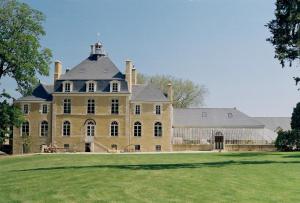 un grand bâtiment jaune avec une tour au-dessus d'un champ dans l'établissement DOMAINE LE MEZO, à Ploeren