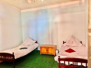 um quarto com duas camas e uma mesa de cabeceira com uma mesa em Ismayilli Bag Evi, Vacation Home em Ismailli