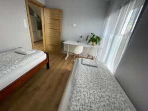 兹邦申Apartament_Zbąszyń的一间卧室，有两张床、一张桌子和一扇窗户
