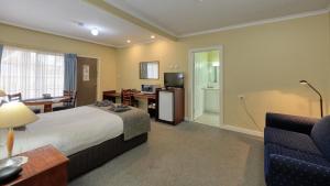 a hotel room with a bed and a living room at Oasis Motor Inn in Broken Hill
