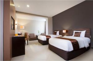 a hotel room with two beds and a chair at Regantris Malioboro in Yogyakarta