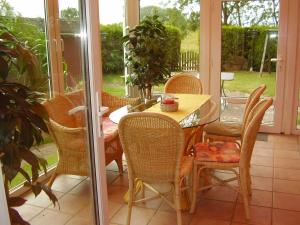 un porche con mesa de madera y sillas en Ferienhaus in Nessmersiel 80-048, en Nessmersiel