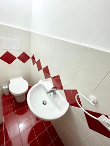 - une salle de bains rouge et blanche avec toilettes et lavabo dans l'établissement Conte125, à Cinisi