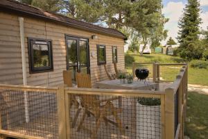 a house with a fence and a table on a deck at AZUR Camping Schwäbische Alb in Sonnenbühl