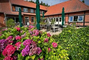 a garden with flowers and green umbrellas in front of a building at Sallingsund Færgekro in Nykøbing Mors