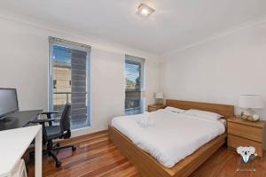 シドニーにあるKozyGuru / Allawah / 2 Bed Kozy APT / NAL015のベッドルーム1室(ベッド1台、デスク、コンピュータ付)