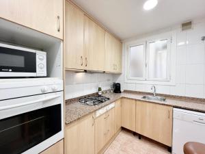a kitchen with wooden cabinets and a microwave and a sink at Villa Olimpica Beach in Barcelona