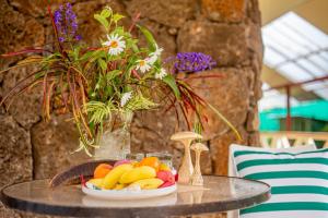 stół z talerzem owoców i wazonem kwiatów w obiekcie Hostal Uruhao w mieście Hanga Roa