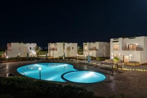 a large swimming pool in front of some buildings at night at Olives at Santa Monica in Marsa Matruh +39 photos