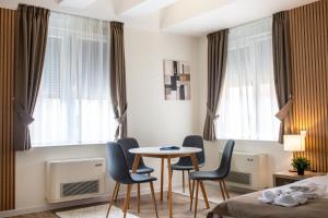 Habitación de hotel con mesa, sillas y ventanas en Zona Optimizma accommodation & SPA, en Vršac