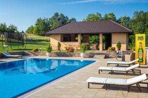 a swimming pool with chairs and a house at Apartments Lucija in Slunj