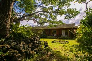 uma casa com uma parede de pedra em frente a um quintal em Hostal Uruhao em Hanga Roa