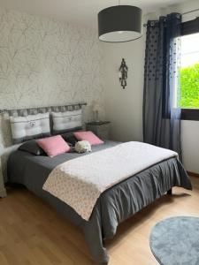 a bedroom with a bed with pink pillows at Les voyages de Louison in Lavardac